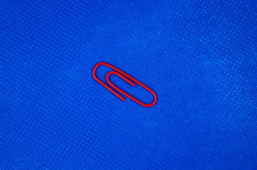 Eine rote Kunststoff Büroklammer mit blauem Hintergrund