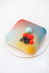 Elegance square velour mousse cake. nut and fruit filling inside. Contemporary colorful pie. selective focus. white marble table