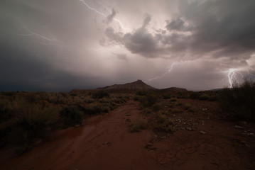 One bolt of lightning strikes in the distance while another zigzags across the sky lighting the...