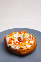 donut in sugar glaze with candied fruits on a blue plate