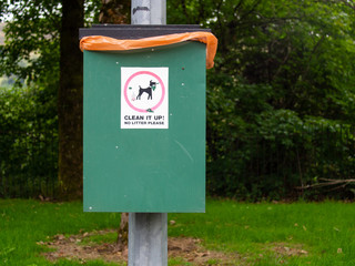 Fototapeta na wymiar Green dog mess litter bin in a park