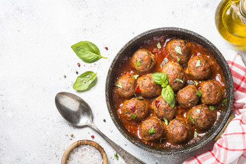 Meatballs in tomato sauce on white table.