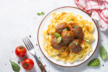 Naklejka premium Meatballs in tomato sauce with pasta tagliatelle top view.
