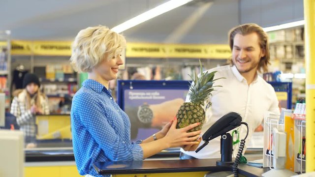 Blonde attractive woman at the supermarket checkout, she is paying using a credit card, shopping and retail concept.
