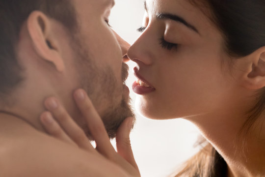 Close up of sensual young couple facing each other close to kiss, girlfriend touching boyfriend chin enjoying intimate moment together, romantic lovers with eyes closed having tender love foreplay