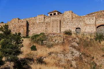 Fototapeta premium External view of Alcazaba Walls - palatial fortress in Malaga built in XI century. Fortress palace, whose name in Arabic means citadel, is one of city's historical monuments. Malaga, Andalusia, Spain.