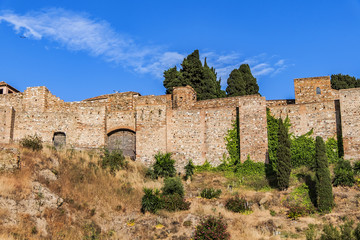 Fototapeta premium External view of Alcazaba Walls - palatial fortress in Malaga built in XI century. Fortress palace, whose name in Arabic means citadel, is one of city's historical monuments. Malaga, Andalusia, Spain.