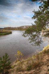 Landscape autumn, the river against the backdrop of a panoramic view of the valley. High steep bank with pine trees.