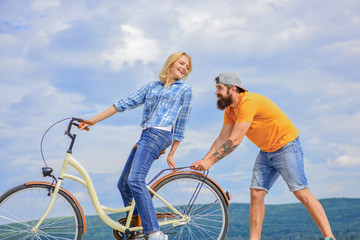 Cycling service. Mechanic helps maintain bicycle. Supportive service. Woman rides bicycle sky background. Man helps keep balance ride bike. Girl cycling while man support her. Service and assistance