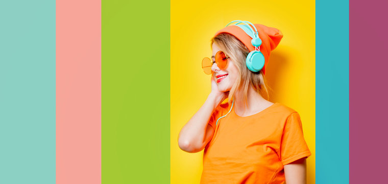 Young style girl with orange glasses and headphones on color background. Clothes in 1980s style
