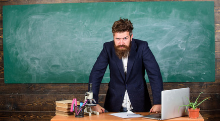 Teacher interesting interlocutor as authority. Teacher bearded man tell scary story. Teacher charismatic hipster stand near table classroom chalkboard background. Talking to students or pupils