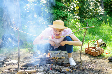 Girl hungry tourist can not wait when food will be roasted. Woman in straw hat try to bite sausage...