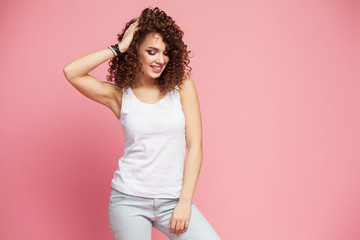 Image of happy young lady standing isolated over pink background. Looking camera pointing.