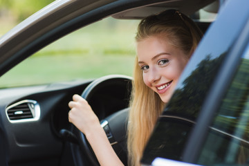 Very happy young blondy girl driving car