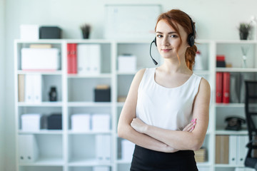 Beautiful young girl in headphones with microphone standing in office.