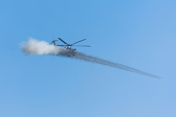 Fototapeta na wymiar Military helicopter makes a shot with a volley from several missiles with smoke.