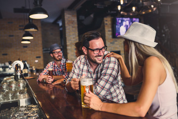 Young cheerful people in the beer pub drinking and having good time. Friendship concept with young people enjoying time together and having genuine fun at cool vintage pub 