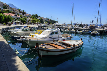 Fototapeta na wymiar Fishing and pleasure boats on the pier in the resort town of Brela in Croatia.