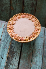 Homemade pie with cream filling and apple roses on old wooden blue background