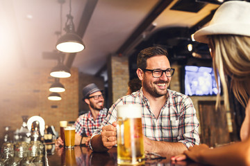 Happy friends having fun at bar - Young trendy people drinking beer and laughing together
