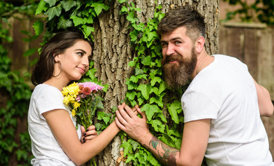 Obraz premium Pleasant date in nature environment. Man bearded hipster holds hand girlfriend. Couple in love romantic date walk nature tree background. United with nature. Couple in love lean on trunk with ivy