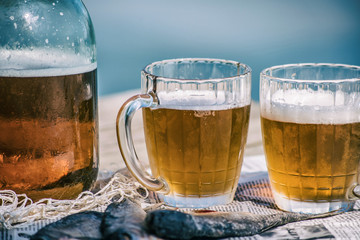 Beer in a jar and in mugs with dried fish