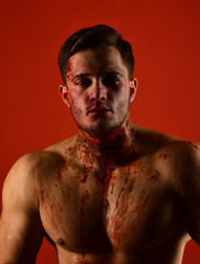 Man with serious face and naked chest on red background.