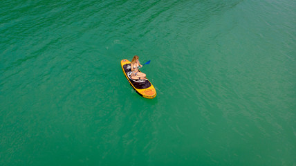 vue aérienne au dessus d'une jeune femme blonde  qui rame assise sur son paddle