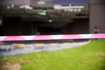 Red and white Barricade tape defining border of restricted area of construction work in progress.marketing ribbon on wrapped on wooden poles in landscape, construction site.