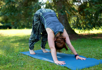 Fototapeta na wymiar A woman is practicing yoga in the park. Poland