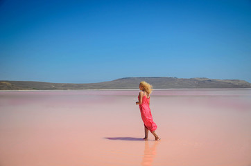 The woman in red dress walking on pink lake in Crimea
