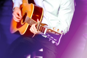 Obraz premium Golden Blues.Guitar with a man's male hands playing live the guitar on wooden wall background, electric or acoustic guitar with nature light. Concept of folk jazz guys boys band performing on events 