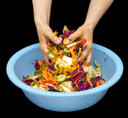 woman preparing salad with fresh vegetables. Preparation of tasty and healthy food on a black background