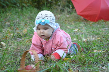 Portrait of happy little baby girl playing at natural outdoors park background. baby girl in autumn park in pink raincoat with red umbrella.