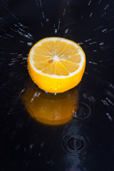 Splashing water against a tasty lemon on a black background