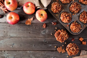 Autumn corner border with warm apple caramel muffins. Top view table scene on a rustic wood background. Copy space.