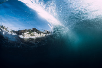 Barrel wave crashing in tropical ocean with sunlight. Underwater view