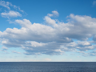 Naklejka na ściany i meble Clouds in blue sky over sea