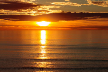 Golden dramatic sunset sun reflecting orange, gold, blue off calm ocean
