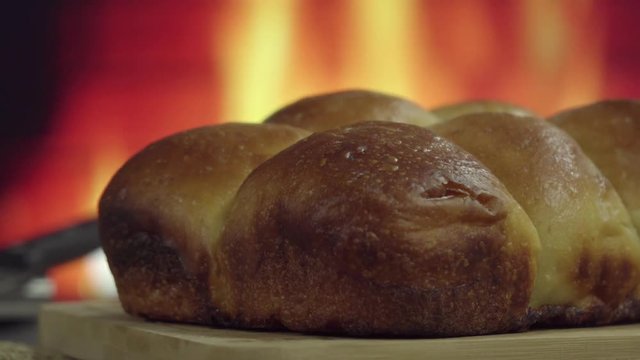 Brazilian Homemade bread on top of a wooden countertop in front of fire in 4k. Copy Space. 