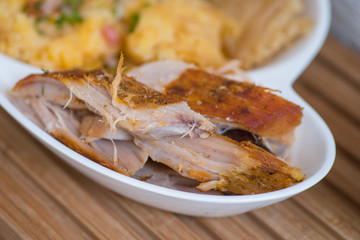 Close up of typical Andean food hornado inside of a white plate with mashed potatoes with salad