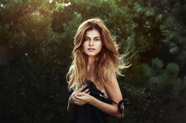 Gorgeous woman with natural beauty in forest with windy long healthy hair and natural makeup