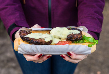 Close up photo of an open sandwich with lamb meat, rocket salad, tomato, and aioli garlic mayonnaise sauce at a street food market