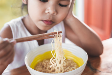 Cute asian child girl bored to eat Instant noodles for her meal