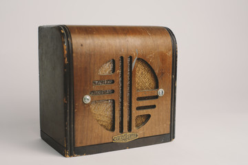 Old antique wooden radio with speaker on a plain backdrop