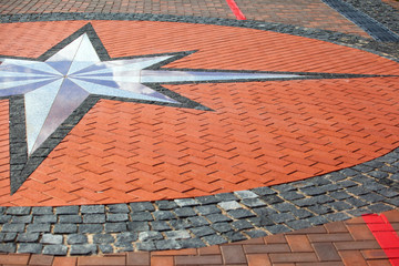 a sign of wind rose on a sidewalk tile