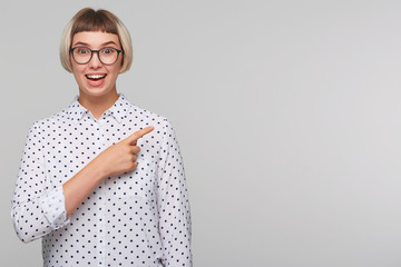 Closeup of happy beautiful blonde young woman wears polka dot shirt and spectacles feels excited...