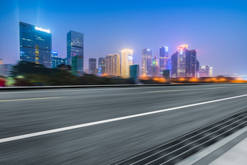 Fototapeta na wymiar blurred asphalt road with city skyline background at night
