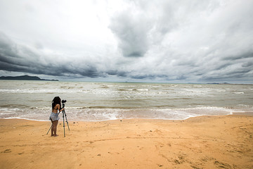 Photographer taking photo Cloudy storm in the sea before rainy. Woman photographer shooting with tripod and DSLR camera in Cloudy storm with beautiful landscape. Huge storm clouds with rain .