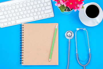 Top viwe of modern workplace with stethoscope and keyboard on blue table background. Flat lay...
